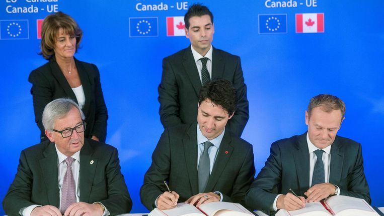 De Canadese president Trudeau (midden) en Europese leiders Jean-Claude Juncker (links) en Donald Tusk (rechts) tekenen het Ceta-verdrag. Beeld afp