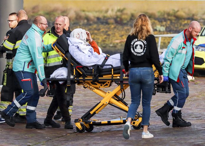 Een geredde passagier van de betrokken watertaxi omringd door reddingswerkers in de haven van Harlingen.