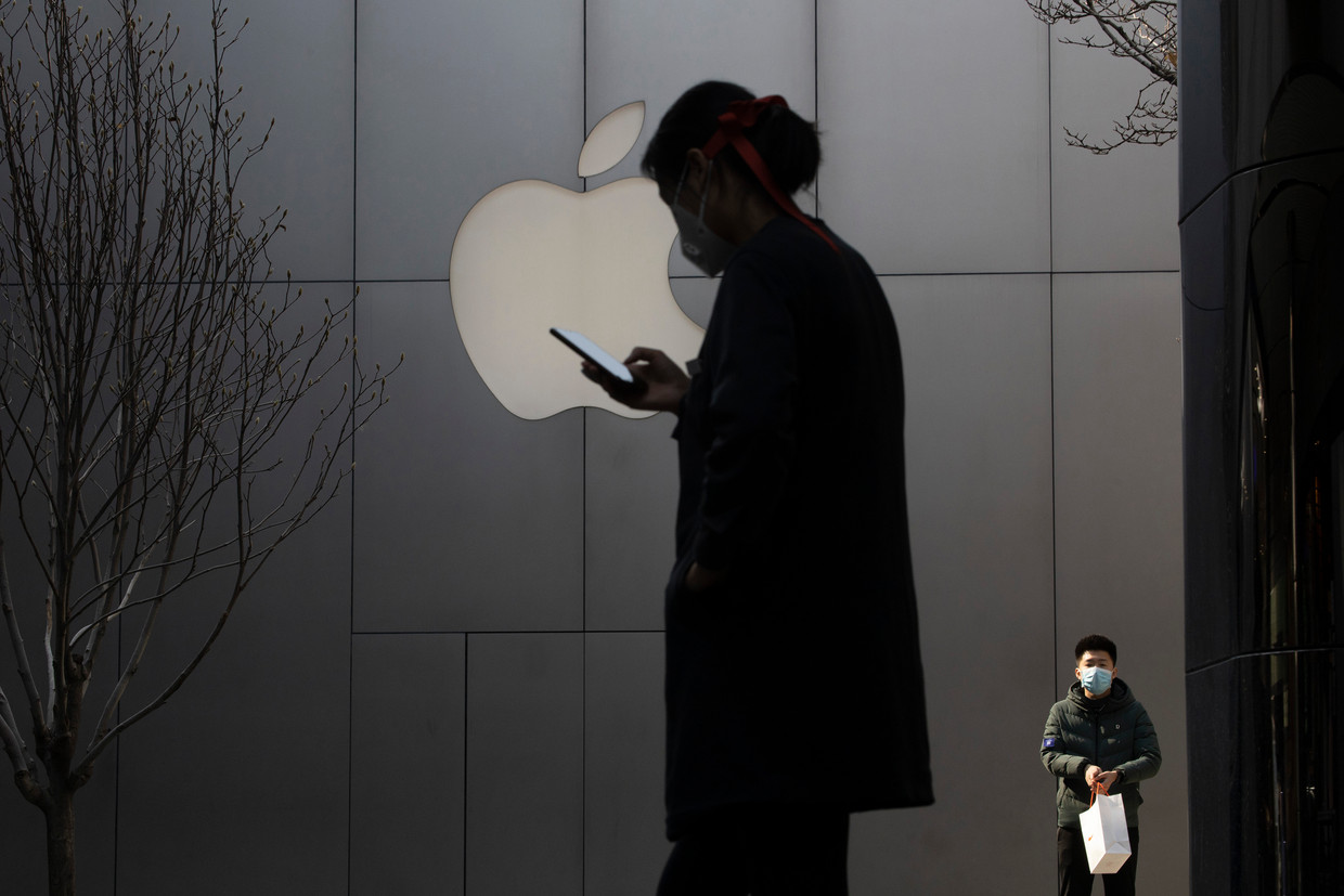 Een vrouw gebruikt haar telefoon in de buurt van de Apple Store in Peking. Beeld AP