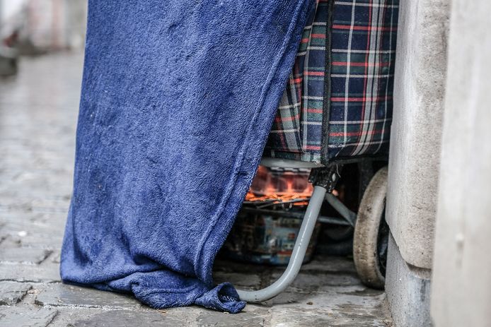 Een dakloze probeert zich warm te houden in Brussel.