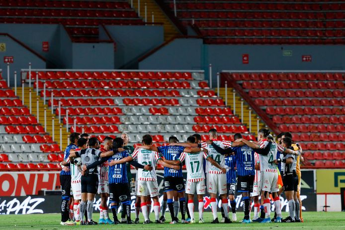 Spelers van Necaxa en Queretaro (blauw-zwarte shirts) vinden elkaar in een collectieve omhelzing.
