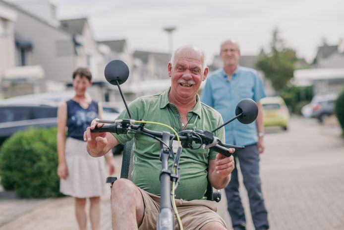 Met zijn op maat gemaakte driewieler is Ton Hoendervangers een vertrouwde verschijning in zijn buurt. Links achter hem zijn vrouw Mieke, rechts John Zwetsloot. John zit in het bestuur van de Ataxie Vereniging Nederland.