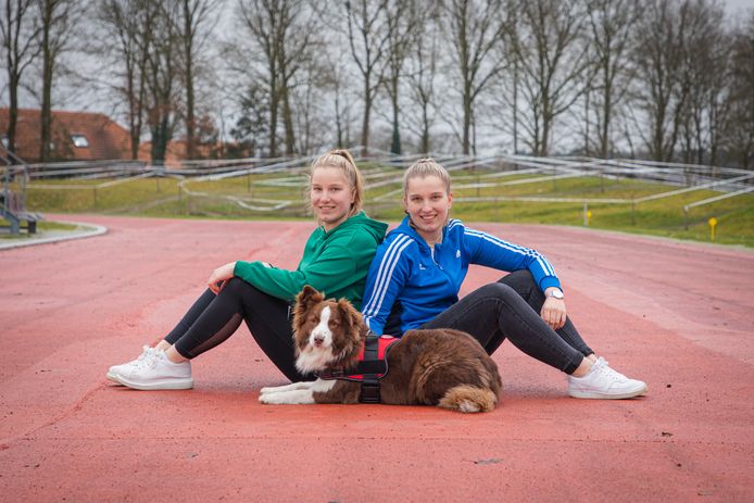 Anna (l) en Nina Bijl met hond Charlie op de atletiekbaan in Reusel.