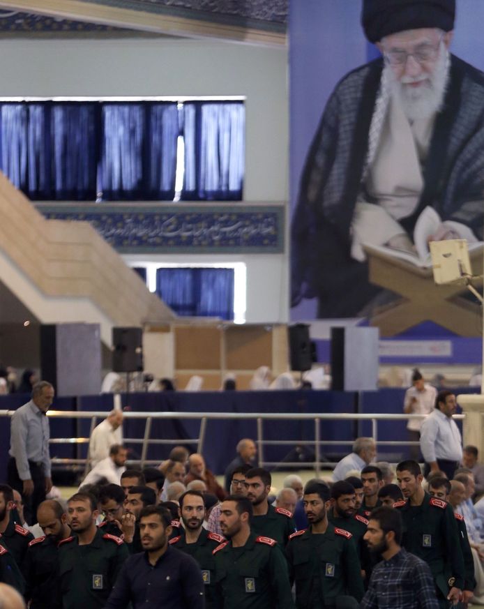 Met op de achtergrond een grote beeltenis van de Iraanse Opperste Leider, ayatollah Ali Khamenei, nemen leden van de Republikeinse Garde deel aan het vrijdaggebed in een moskee in Teheran. De Garde, Khamenei's eigen leger, speelt een cruciale rol in de ‘tankeroorlog'. Foto AFP