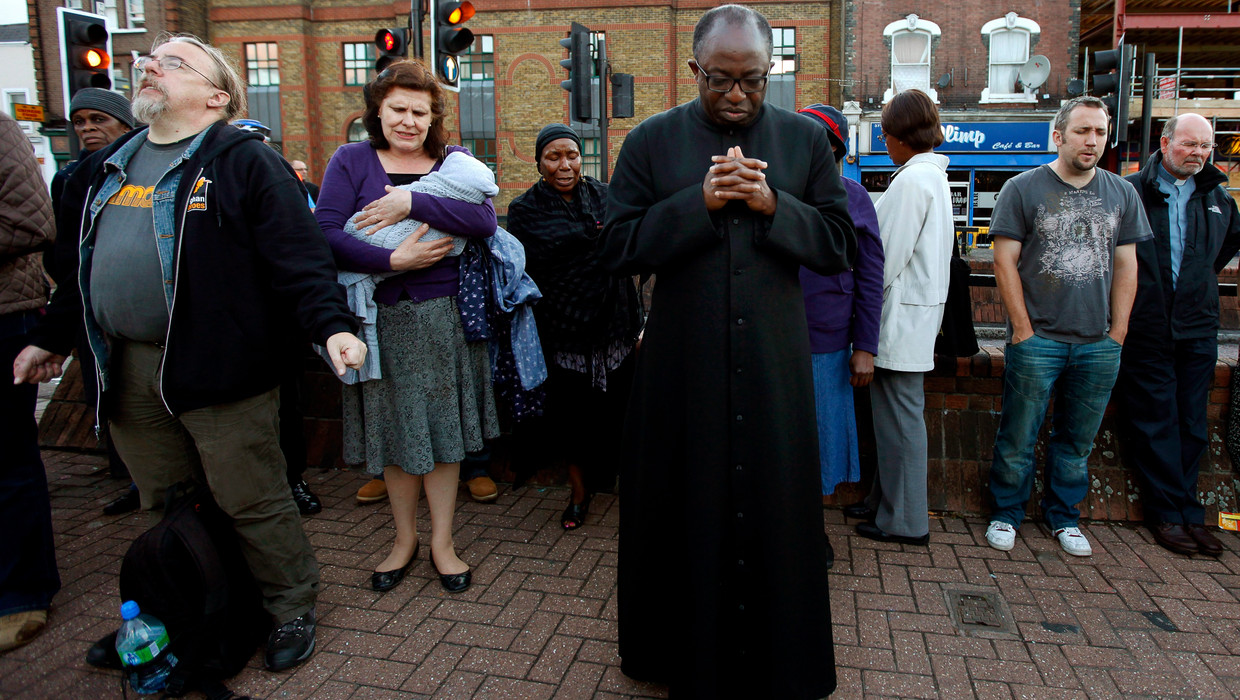 Kerkgangers bidden op straat voor een kerk in Tottenham. Beeld EPA