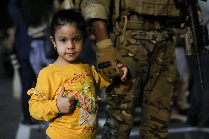 Een meisje houdt de hand van een soldaat vast en steekt haar duim op nadat ze geëvacueerd werd uit Soedan.