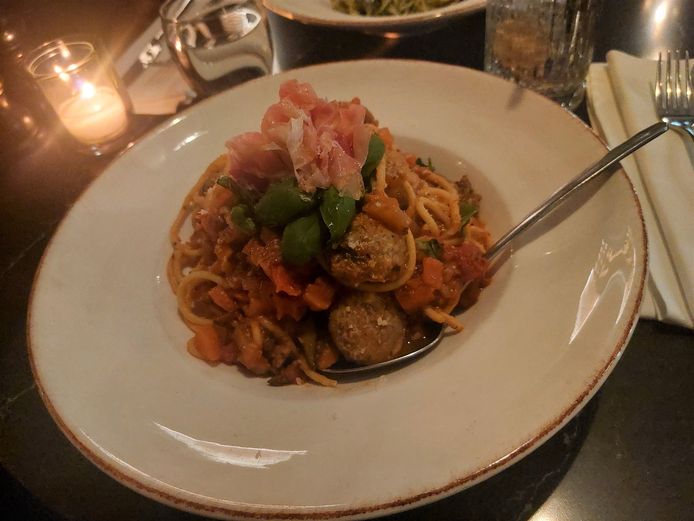 De huisgemaakte gehaktballetjes met tomatensaus en pasta, afgewerkt met parmaham en basilicum.
