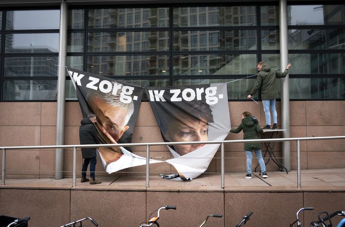 Een spandoek wordt opgehangen voorafgaand aan een kort geding waarin de vakbonden CNV en FNV een compensatieregeling eisen voor zorgmedewerkers die arbeidsongeschikt zijn geraakt door langdurige covid.