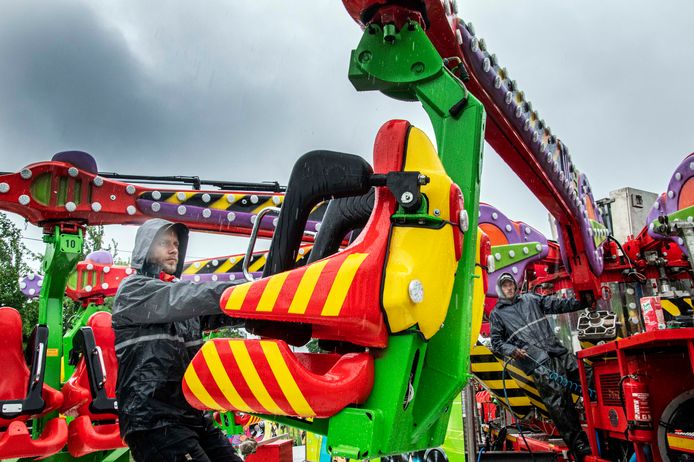 Natte pakken en gure blikken bij de opbouwers van de kermis.