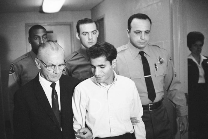 Schutter Sirhan Sirhan op 28 juni 1968 voor een van de rechtszittingen in Los Angeles, begeleid door zijn advocaat (links) en enkele agenten.