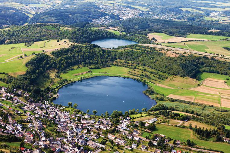 Op de voorgrond: het Weinfelder Maar, een cirkelvormig water in de Eifel dat ooit ontstond na een vulkanische eruptie.   Beeld Getty Images/Westend61