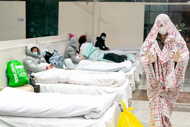 Een coronapatiënt loopt door de hal van het ziekenhuis in de Chinese provincie Wuhan.  Beeld AFP