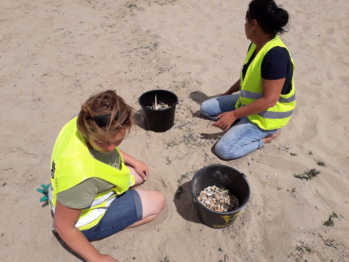 Op je knieën de peuken uit het zand halen.
