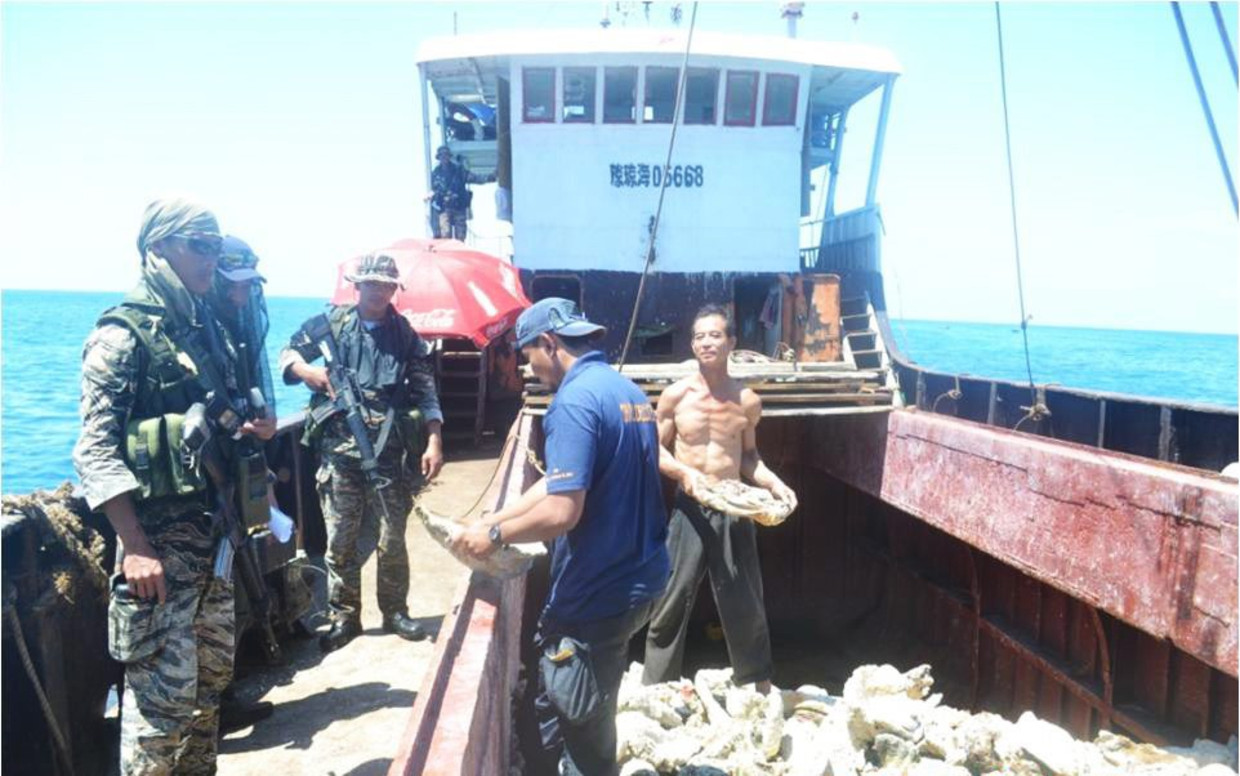 Bewapende Filippijnse controleurs inspecteren een Chinese trawler. Beeld EPA