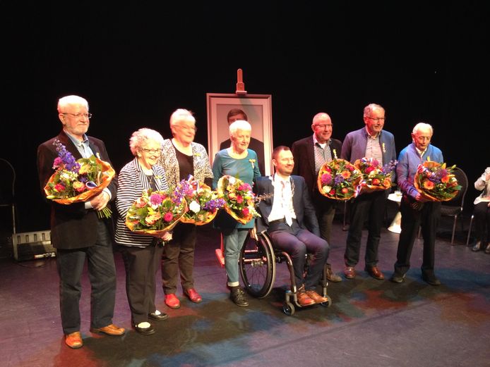 Zeven nieuwe Leden in de Orde van Oranje Nasssau en één burgemeester (met achter hem de koning).
