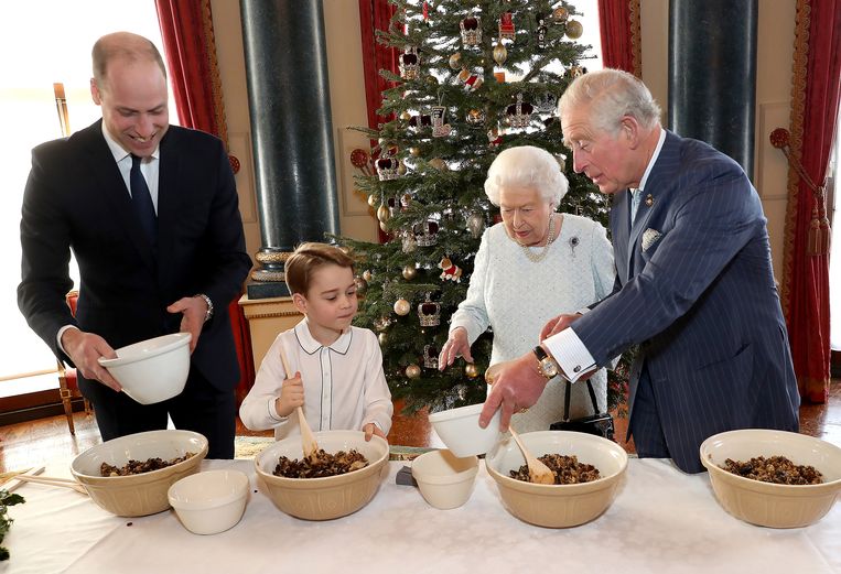 Het Britse koningshuis werkte gisteren in Buckingham Palace aan de traditionele kerstpudding. De 93-jarige koningin kijkt toe hoe haar achterkleinzoon George de ingrediënten voor de pudding door elkaar husselt. Troonopvolgers Charles en William helpen ook een handje. Beeld EPA