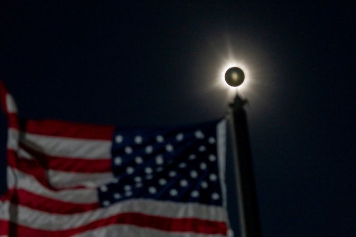 Een totale zonsverduistering boven een Amerikaanse vlag in Houlton, Maine, in de Verenigde Staten.