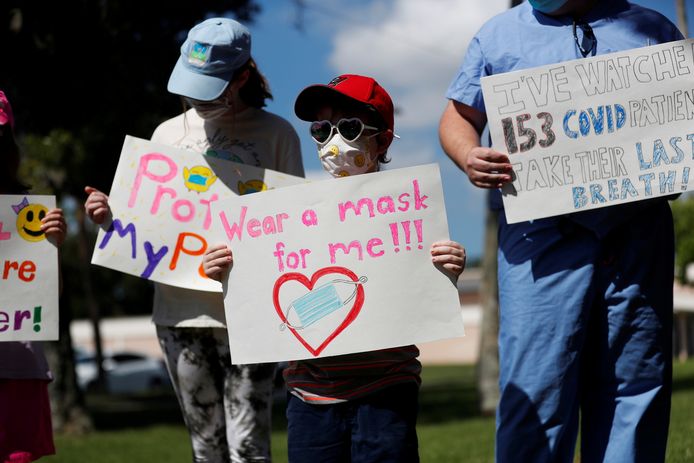 Leerlingen Sofia Deyo (11) en haar broertje Matthew Deyo (6) demonstreren aan hun school in Largo, Florida, voor het dragen van een mondkapje.