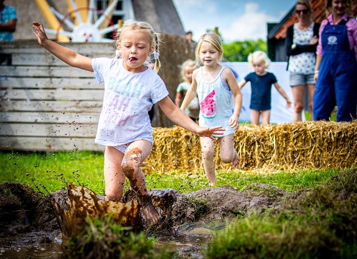 Kinderen kruipen en springen door de modder tijdens een zomervakantie bij Avonturenboerderij Molenwaard.