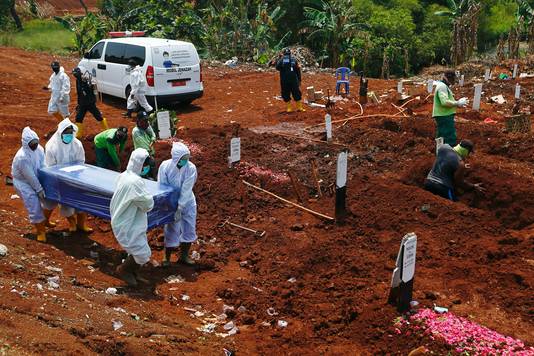 Werkers in beschermingspakken op een begraafplaats voor coronaslachtoffers  in Jakarta, Indonesië.