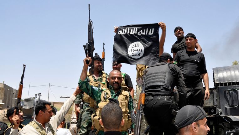 Iraakse soldaten tonen een buitgemaakte IS-vlag. Beeld REUTERS