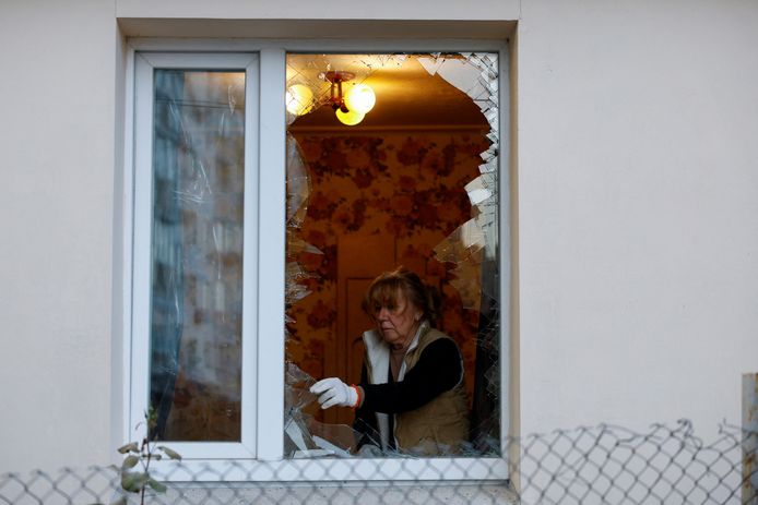 Een vrouw verwijdert glassplinters uit haar raam na de aanval.