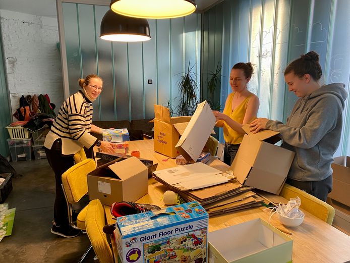 Aan de livingtafel worden dozen geplooid door Marie (15), en de mama's Tine en Karolien
