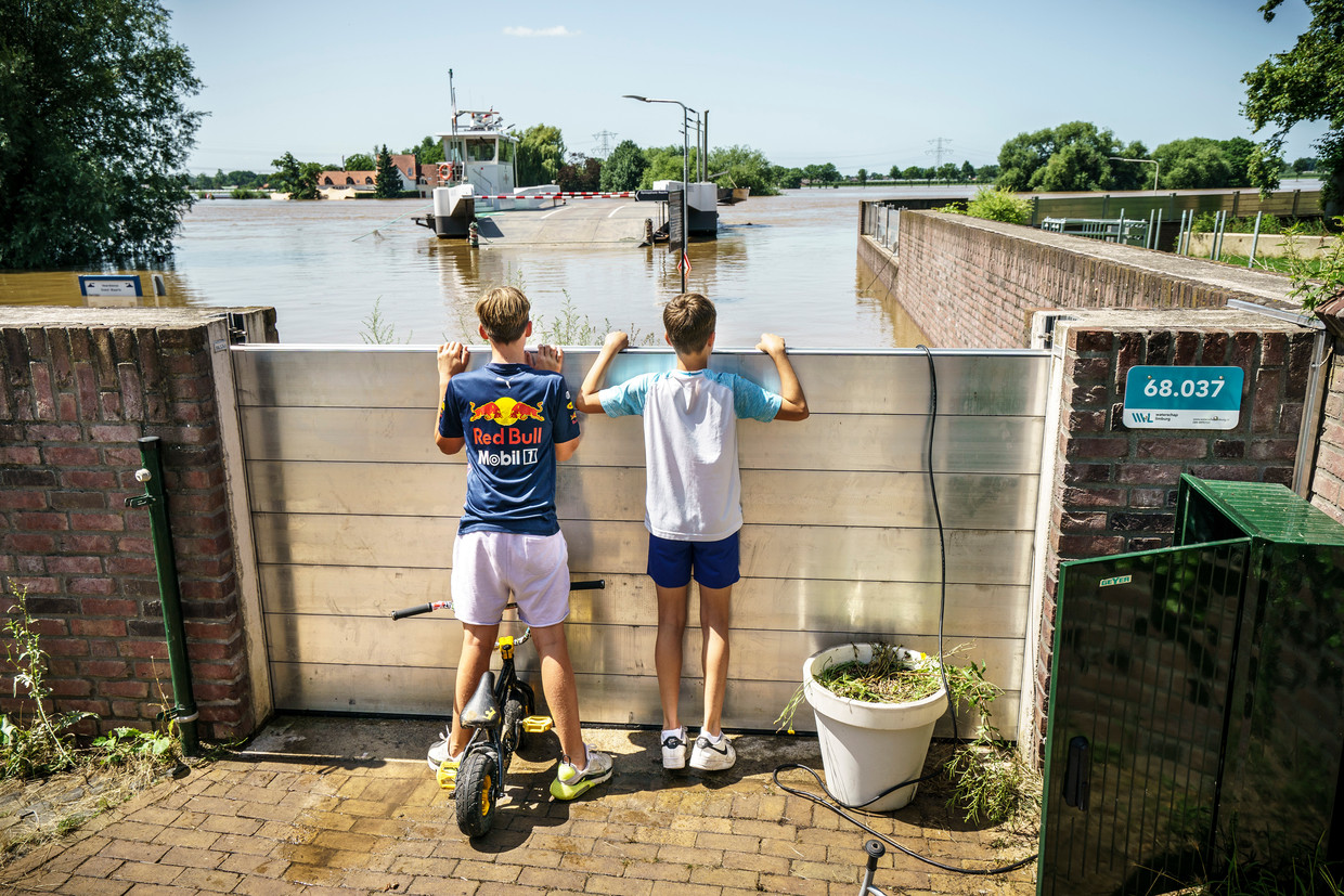 Nieuwsgierige jongens kijken naar het hoge water achter de metalen beschermschotten.
Foto: Maikel Samuels Beeld Maikel Samuels