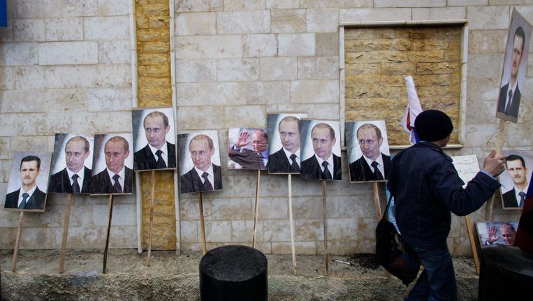 Foto's van Poetin en Assad staan tegen de muur van de ambassade van Damascus voor aanvang van een pro-Syrisch protest in 2013. Beeld AP