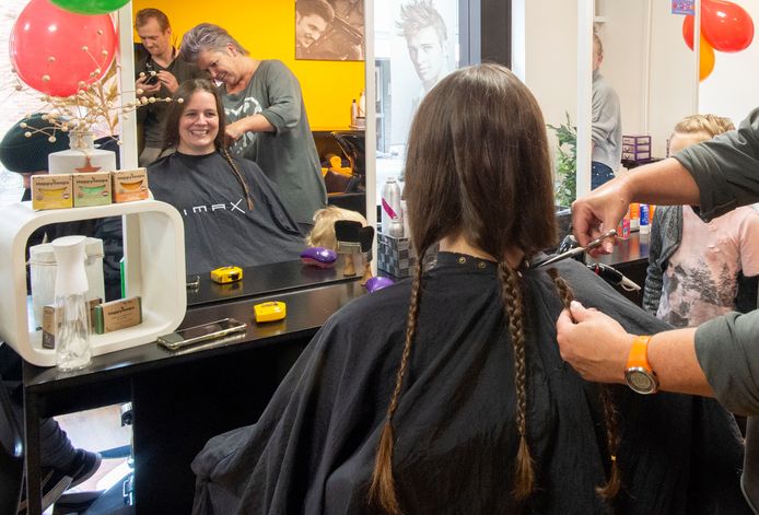 Rieke Oudejans doneert haar vlechten aan het goede doel. Kapster Miriam van Ruiten van kapsalon Geknipt zet de schaar erin.