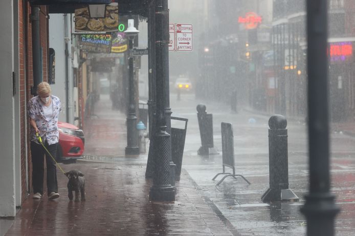 Een vrouw laat haar hondje uit in New Orleans terwijl orkaan Ida aan land gaat.