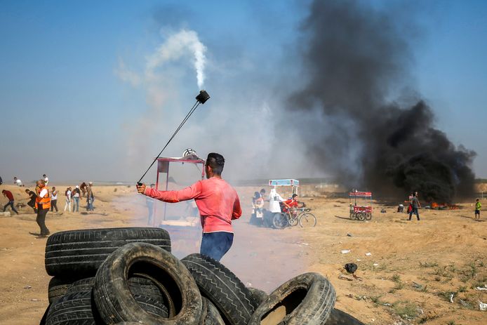 Een Palestijnse betoger gebruikt een slinger om een traangasgranaat terug te gooien naar Israëlische troepen.