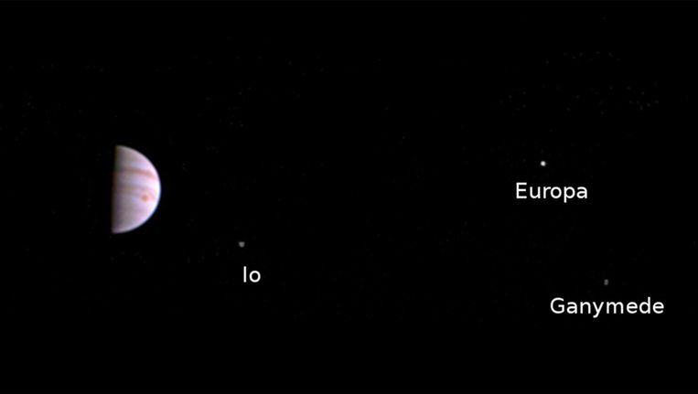 Foto gemaakt door Juno waarop een deel van Jupiter te zien is en drie van de vier grootste manen. Beeld NASA