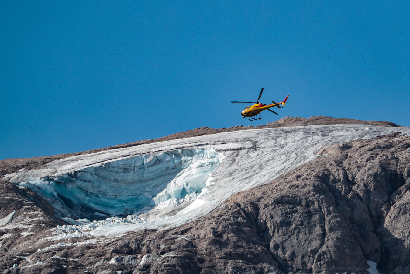 Een reddingshelikopter vliegt over de gletsjer op de berg Marmolada, de hoogste in de Dolomieten, waarvan zondag een stuk afbrak.