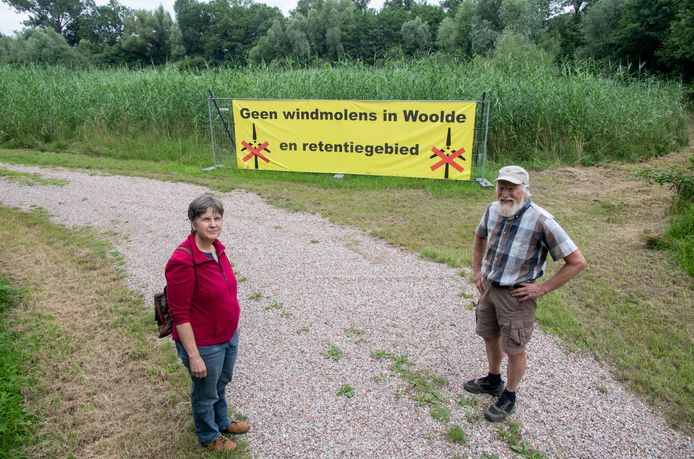De strijd tegen de mogelijke komst van windmolens in Woolde gaat door. Hier twee initiatiefnemers van het eerste uur, Mariska van Doorn en Piet Vendel, bij een spandoek in het retentiegebied.
