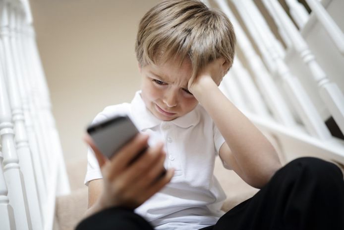 Een jongetje ontvangt pesterige berichtjes op zijn smartphone.