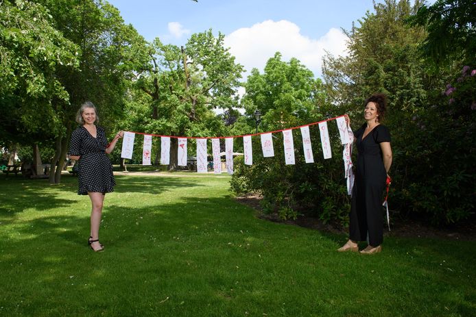 Beeldend kunstenaar Willemien Nijman (rechts) en Danielle van der Stelt (Palthe Huis) met een aantal geborduurde slingers waarop een positieve boodschap staat afgebeeld.
