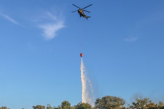 Een helikopter van Defensie helpt bij het blussen van de brand.