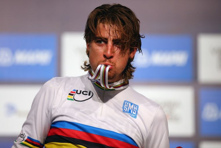 Wereldkampioen Sagan eet zijn medaille op nadat hem net de regenboogtrui is aangemeten. Beeld anp