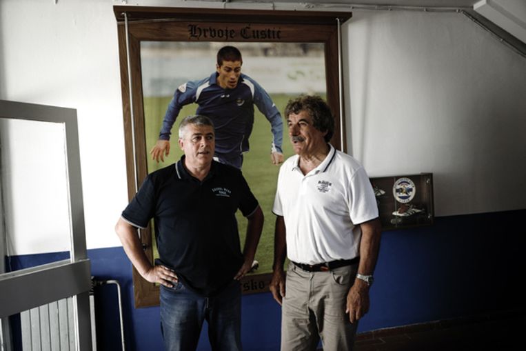 Directeur van NK Zadar Svetko Custic (links) en Josip Bepo Baslo, sportief directeur van de club. Achter hen een foto van de zoon van Custic, die overleed na een ongeluk tijdens een voetbalwedstrijd. Beeld Daniel Rosenthal