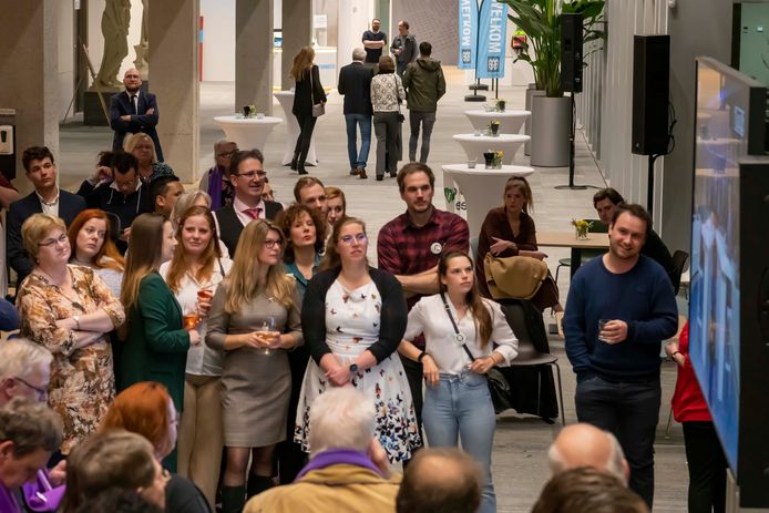 Een beeld van de verkiezingsavond in het Tilburgse stadhuis. Op de voorgrond volgt Partij voor de Dieren de laatste uitslagen. Op de achtergrond begeeft LST-leider Hans Smolders zich met zijn gezin naar de uitgang.