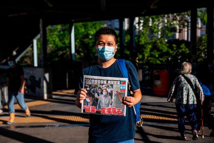 Een man poseert in Hongkong met de Apple Daily van vandaag met daarop een foto van de arrestatie van mediatycoon Jimmy Lai. De oplage is voor vandaag verhoogd tot een half miljoen stuks.