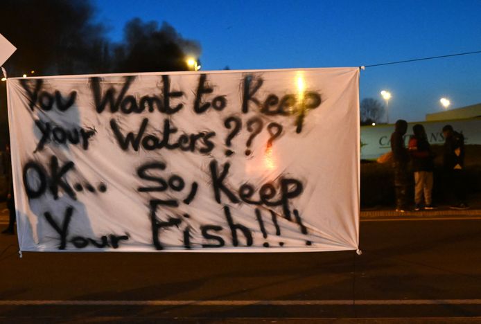 Franse vissers bij een spandoek met de tekst: 'dus jullie willen jullie wateren houden??? oké, maar houd jullie vis dan ook maar' bij een protestactie in Boulogne-sur-Mer.