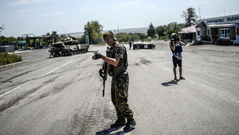 Een Oekraïense soldaat regelt het verkeer in de buurt van de rampplek. Beeld BELGA