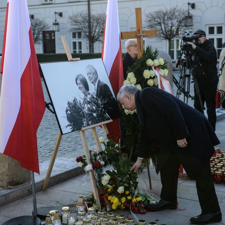 Jaroslaw Kaczynski legt bloemen bij de foto van zijn omgekomen broer en schoonzus. Beeld EPA