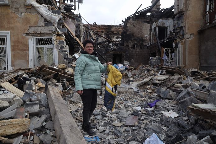 Een vrouw houdt een jasje omhoog terwijl ze tussen de ruïnes staat van het gebouw waar ze woonde, voor het werd vernietigd door Russische aanvallen in Mykolaiv.