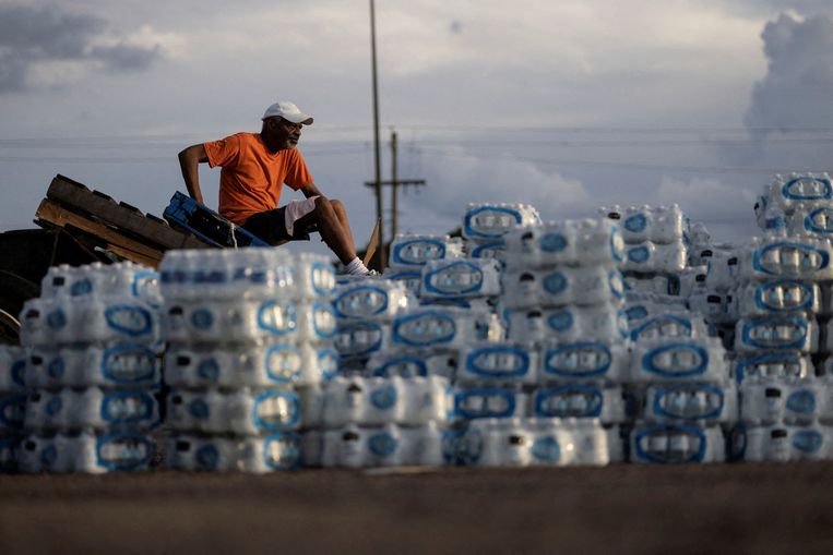 Een vrijwilliger rust even uit tijdens het verdelen van flessen water onder inwoners van Jackson.  Beeld Reuters
