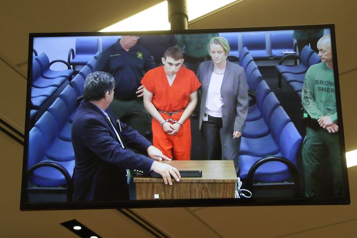 Op een televisiescherm is te zien hoe Nikolas Cruz wordt voorgeleid.