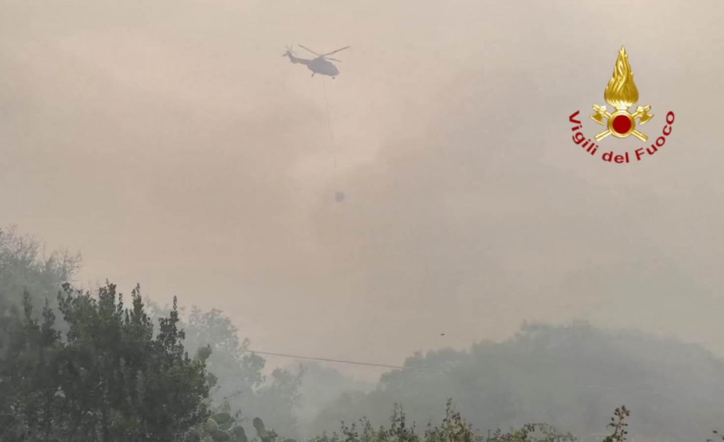 Een blushelikopter aan het werk bij de bosbrand rond de stad Oristano.