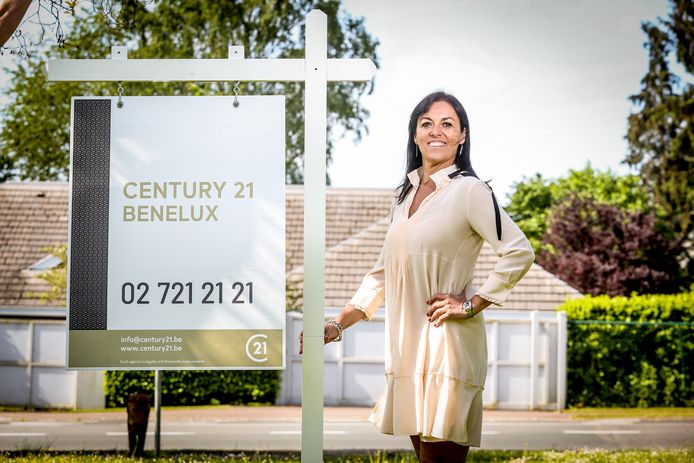 Isabelle Vermeir, ceo van Century 21 Benelux poseert bij een bordje met het nieuwe logo van Century 21.